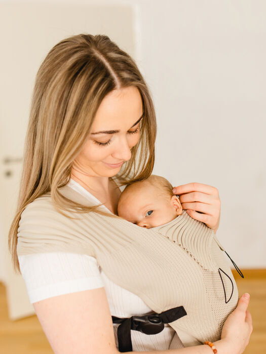 Sarah Klaus trägt ein Baby in einer Babytrage